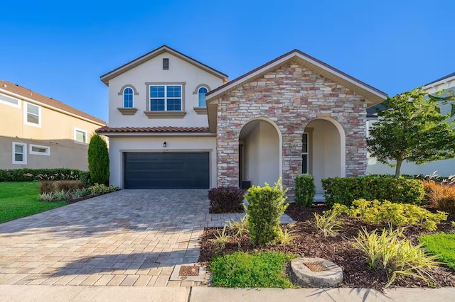 mediterranean / spanish house featuring a garage, decorative driveway, and stucco siding