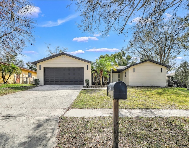 ranch-style house featuring an attached garage, concrete driveway, and a front yard