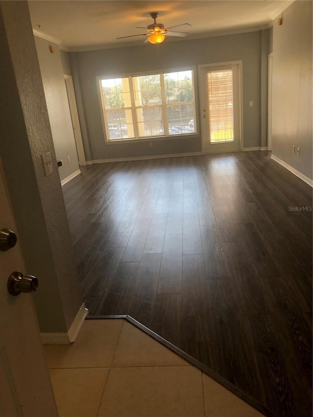 spare room featuring dark wood-style floors, baseboards, a ceiling fan, and crown molding