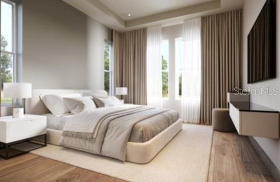 bedroom with a tray ceiling and wood finished floors