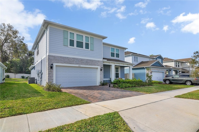 view of front of home featuring an attached garage, stone siding, a front lawn, and decorative driveway