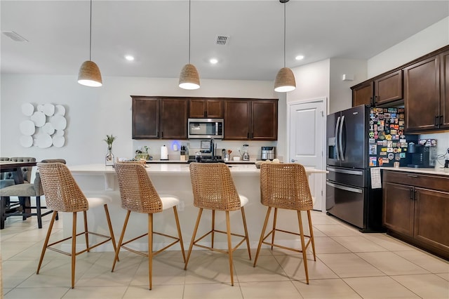 kitchen with visible vents, stainless steel appliances, light countertops, a kitchen bar, and pendant lighting