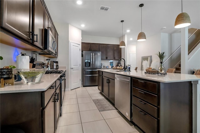 kitchen with stainless steel appliances, a sink, a kitchen island with sink, and pendant lighting