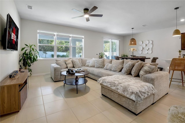 living area featuring ceiling fan, light tile patterned floors, visible vents, and baseboards