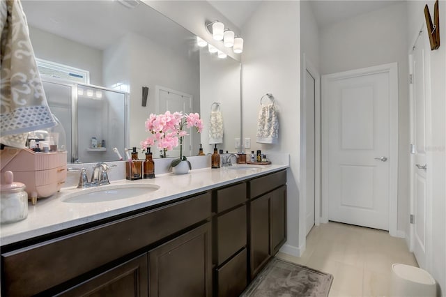 bathroom with a sink, a shower stall, and double vanity