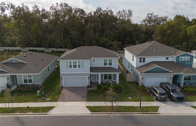 view of front facade featuring decorative driveway, an attached garage, and a front yard