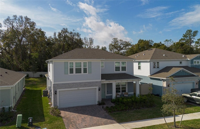 view of front of house with cooling unit, a garage, fence, decorative driveway, and a front lawn