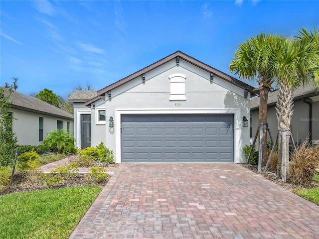 ranch-style house with an attached garage, decorative driveway, and stucco siding