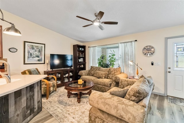 living room with vaulted ceiling, ceiling fan, a textured ceiling, and light wood-style floors