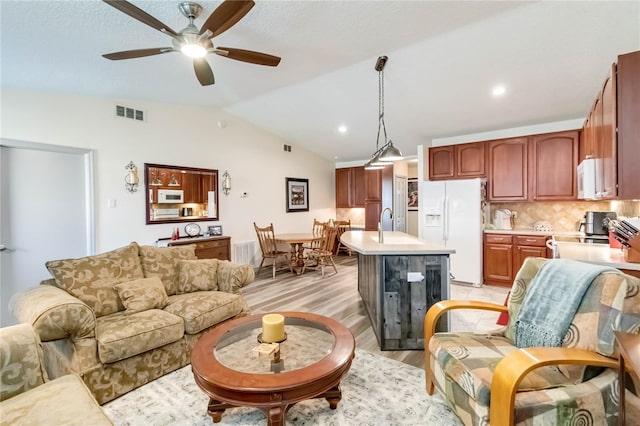 living room with lofted ceiling, visible vents, ceiling fan, and light wood finished floors