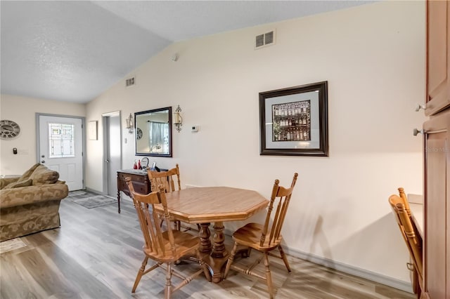 dining area featuring lofted ceiling, light wood-style flooring, and visible vents