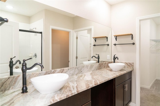 full bathroom with double vanity, a stall shower, and a sink