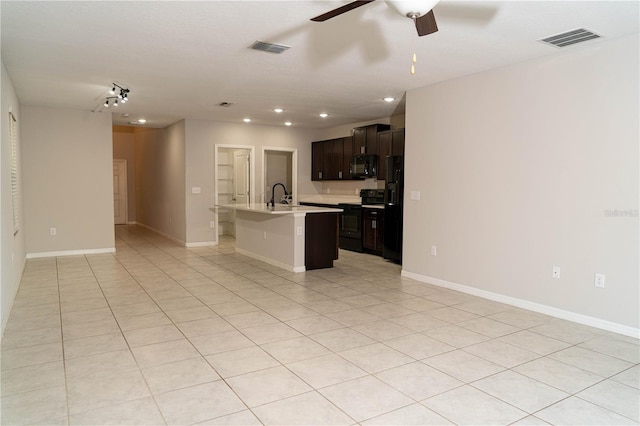 kitchen with black appliances, a center island with sink, light countertops, and open floor plan