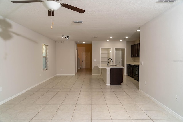 interior space featuring a textured ceiling, light tile patterned flooring, a sink, and visible vents