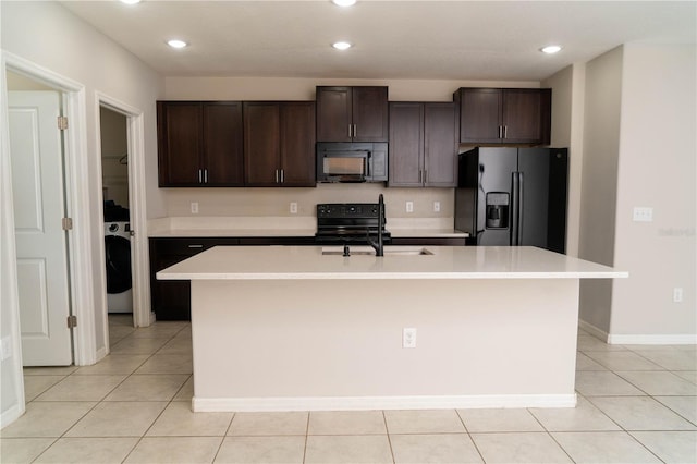 kitchen with a center island with sink, light tile patterned floors, light countertops, dark brown cabinetry, and black appliances