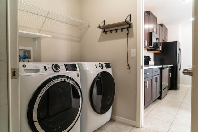 washroom featuring light tile patterned floors, laundry area, washing machine and clothes dryer, and baseboards