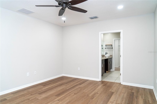 empty room featuring baseboards, ceiling fan, visible vents, and light wood-style floors