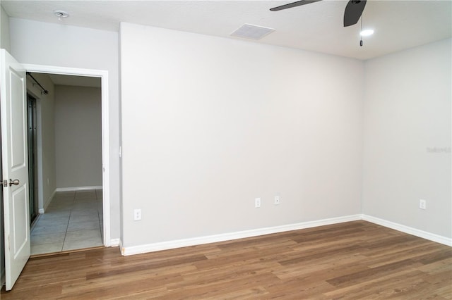 spare room with a ceiling fan, visible vents, baseboards, and wood finished floors