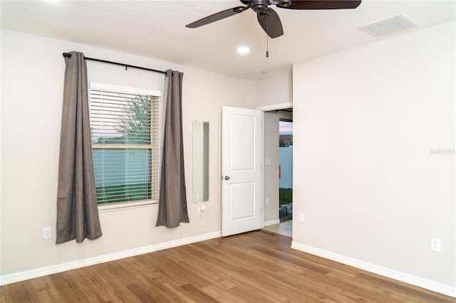 spare room with baseboards, visible vents, ceiling fan, wood finished floors, and a textured ceiling