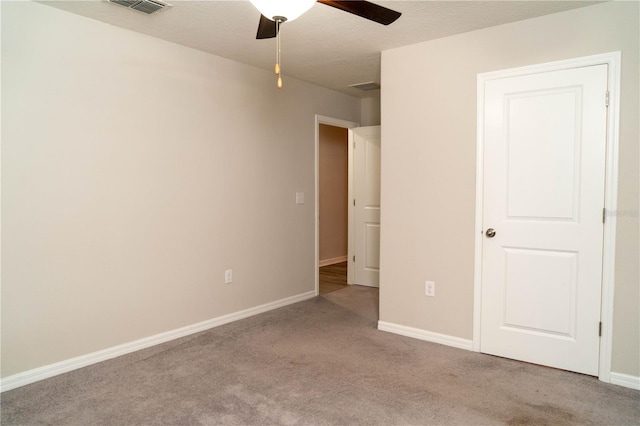 unfurnished bedroom featuring visible vents, light colored carpet, a ceiling fan, a textured ceiling, and baseboards