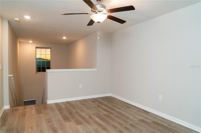 unfurnished room with a textured ceiling, recessed lighting, wood finished floors, visible vents, and baseboards