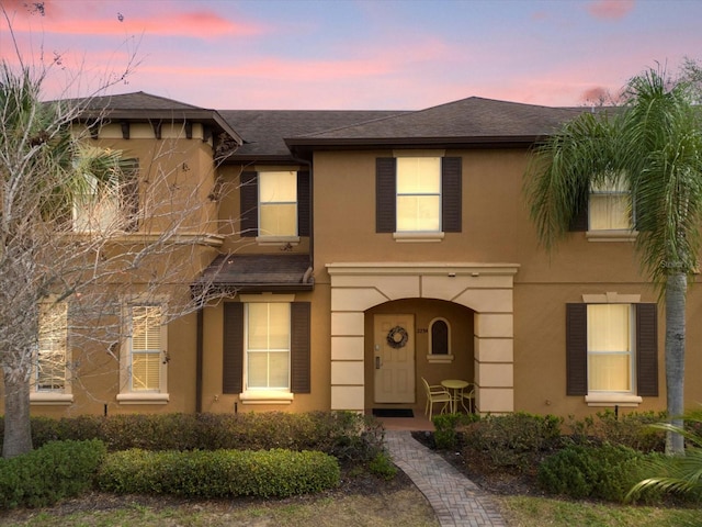 view of front of home with a shingled roof and stucco siding