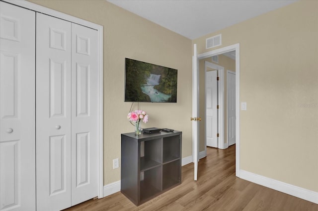 interior space featuring light wood-type flooring, baseboards, visible vents, and a closet