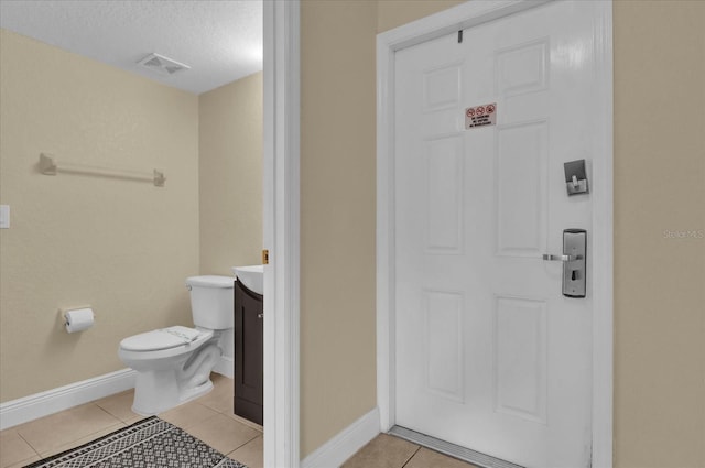 half bathroom featuring visible vents, toilet, vanity, tile patterned flooring, and baseboards