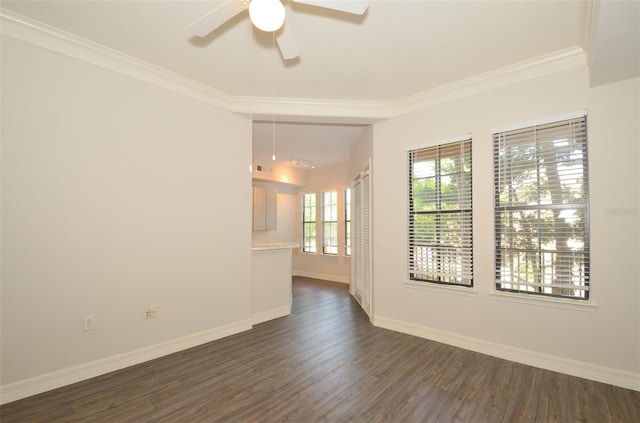 spare room featuring dark wood-style floors, ceiling fan, baseboards, and crown molding