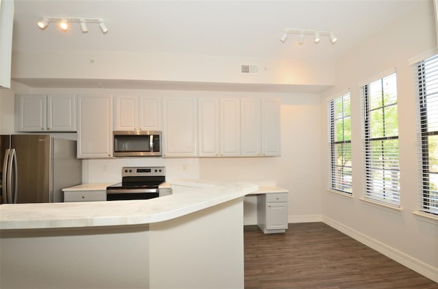 kitchen featuring baseboards, dark wood finished floors, appliances with stainless steel finishes, a peninsula, and light countertops