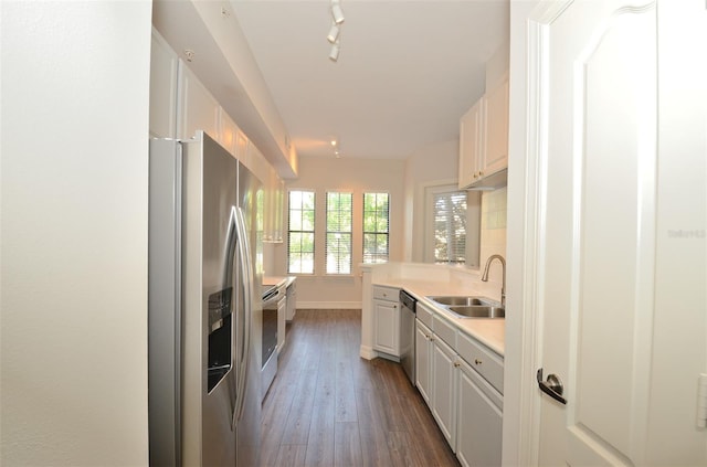 kitchen with a peninsula, stainless steel appliances, light countertops, white cabinetry, and a sink