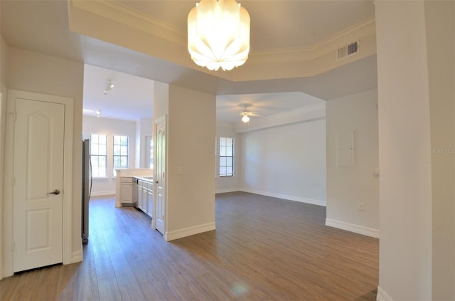 spare room featuring ornamental molding, light wood-type flooring, visible vents, and baseboards