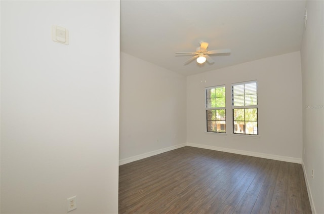 spare room featuring dark wood-style floors, ceiling fan, and baseboards