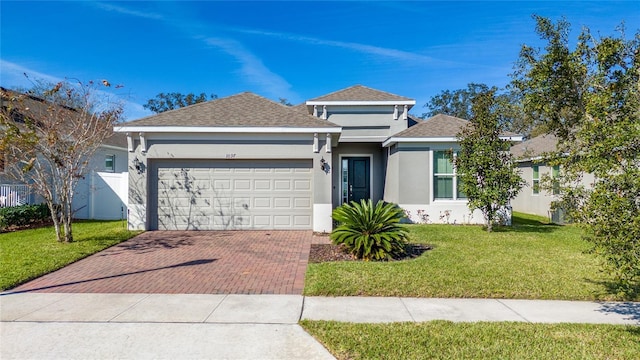 ranch-style house featuring a garage, a front yard, decorative driveway, and stucco siding