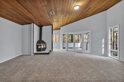 unfurnished living room with wood ceiling, a wood stove, and carpet