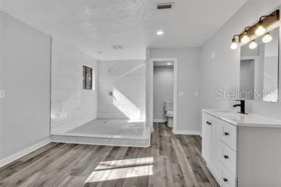 full bath featuring toilet, wood finished floors, visible vents, vanity, and baseboards