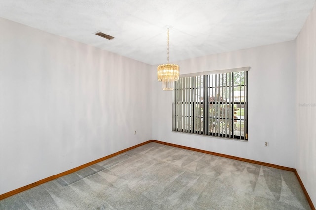 empty room featuring carpet, visible vents, a chandelier, and baseboards