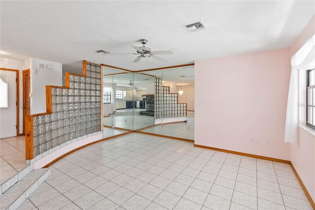 empty room with a ceiling fan, visible vents, a textured ceiling, and light tile patterned flooring