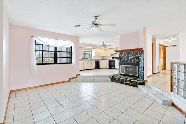 unfurnished living room with baseboards, a stone fireplace, a textured ceiling, and light tile patterned floors