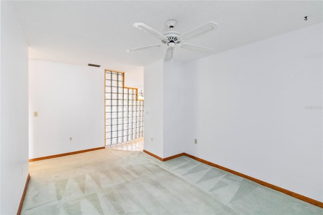 empty room with baseboards, ceiling fan, visible vents, and light colored carpet