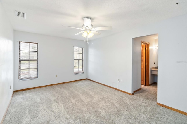 spare room featuring a ceiling fan, visible vents, light carpet, and baseboards