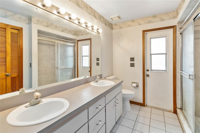 full bathroom with double vanity, a shower stall, a sink, and tile patterned floors