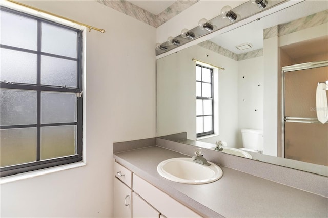 bathroom with toilet, a shower with door, and vanity