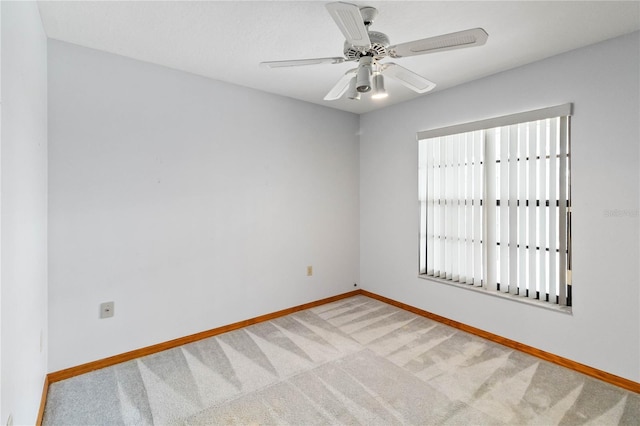 spare room with baseboards, a ceiling fan, and light colored carpet