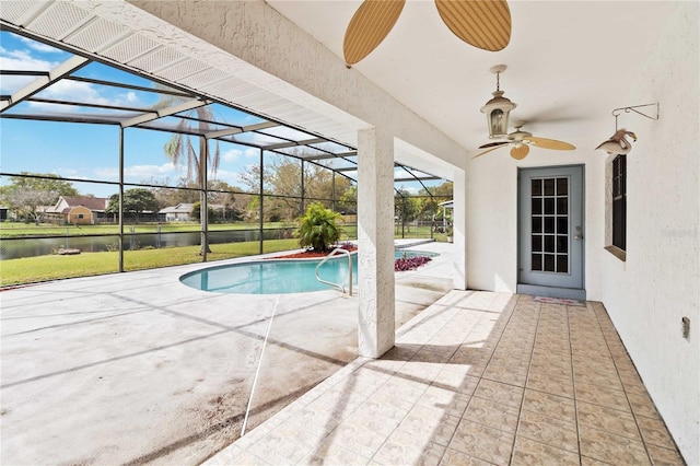 outdoor pool with ceiling fan, glass enclosure, a patio, and a water view