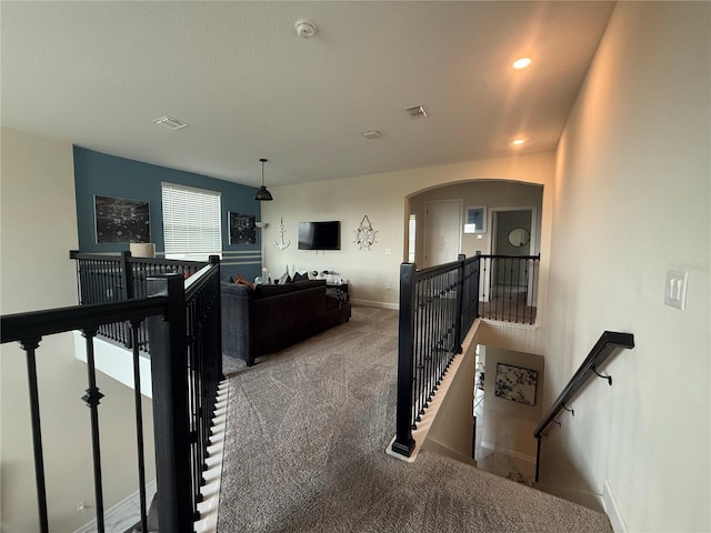 interior space with arched walkways, visible vents, carpet flooring, and an upstairs landing