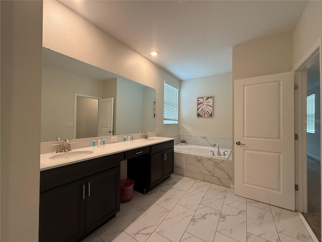 bathroom featuring double vanity, marble finish floor, a garden tub, and a sink