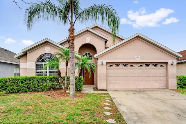 view of front of home with an attached garage, stucco siding, concrete driveway, and brick siding