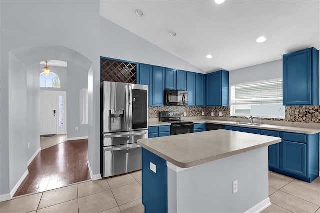 923 Tramells Trl, Kissimmee, FL 34744 - kitchen featuring arched walkways, light tile patterned floors, a sink, a center island, and black appliances