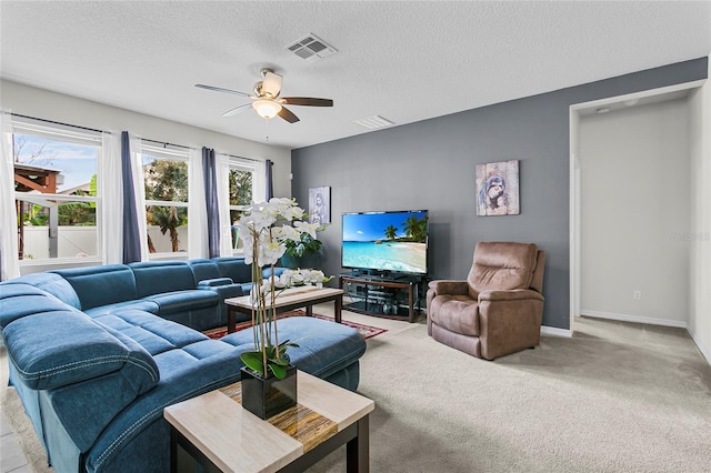 living room featuring light carpet, baseboards, visible vents, a ceiling fan, and a textured ceiling